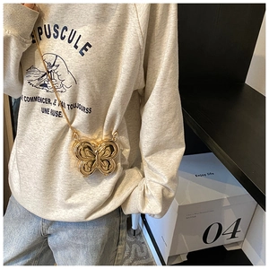 Détail d'un mini sac bandoulière doré en forme de papillon avec une chaîne fine