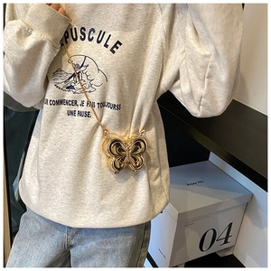 Mini sac de soirée papillon doré chic avec fine bandoulière chaîne porté par un mannequin