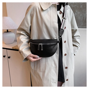 Détail du sac selle noir avec bandoulière rayée et double fermeture éclair argentée