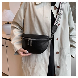 Détail d'un sac bandoulière en cuir grainé noir avec large sangle rayée sur modèle