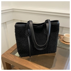 Close-up of black faux shearling tote bag with textured plush finish and leather strap