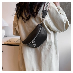 Détail du sac selle en cuir grainé noir avec large bandoulière rayée porté par un modèle
