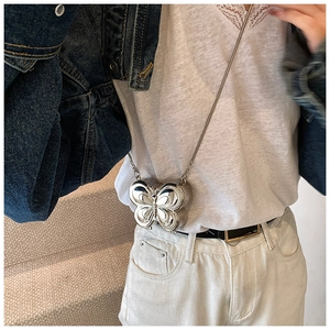 Mini sac papillon argenté avec chaîne, porté par un mannequin dans un style mode Y2K