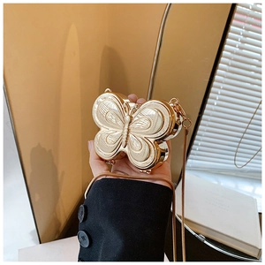 Détail d'un mini sac papillon en métal doré avec une fine chaîne serpentine