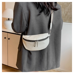 Détail du sac demi-lune blanc avec bandoulière tissée porté sur une veste grise