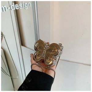 Gros plan du mini sac papillon en métal argenté avec une fine chaîne et un effet miroir poli