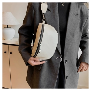 Détail du sac selle beige en cuir grainé avec bandoulière large porté par un mannequin