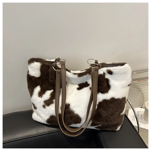 Detail of plush cow print tote bag with brown faux leather handles and silver hardware