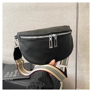 Détail du sac selle en cuir grainé noir avec une large bandoulière rétro rayée