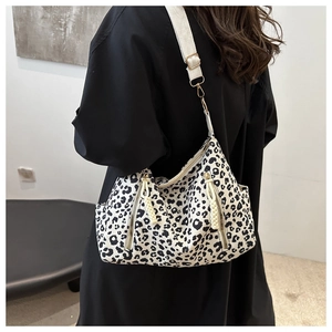 Detail of leopard print canvas crossbody bag with gold hardware and fabric strap