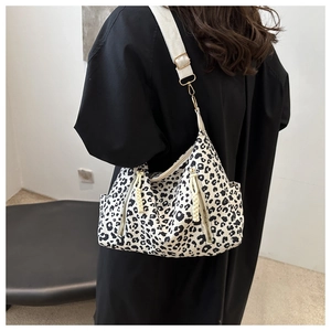 Detail of leopard print tote bag featuring dual front zippers and adjustable wide strap
