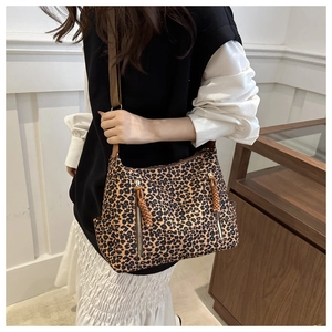 Close-up of leopard print tote bag featuring metal zippers and adjustable nylon strap