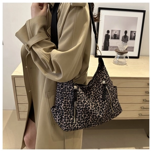Detail of leopard print tote bag with vertical zipper pocket and black woven strap