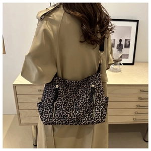 Detail of leopard print tote bag featuring black wide strap and golden metal buckles