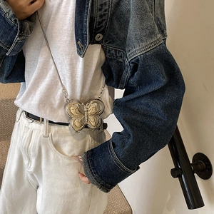 Mini sac papillon argenté au fini métallique porté par un mannequin en veste jean
