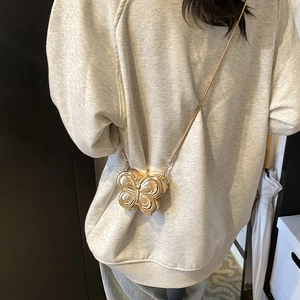 Mini sac bandoulière papillon doré avec chaîne en métal sur la tenue d'un mannequin