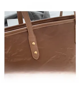 Detail view of the deep brown tote bag showing pleated leather texture and golden rivets