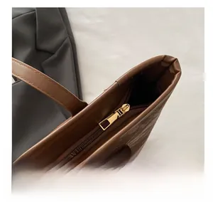 Close-up of smooth gold metal zipper and stitching on the brown leather tote bag