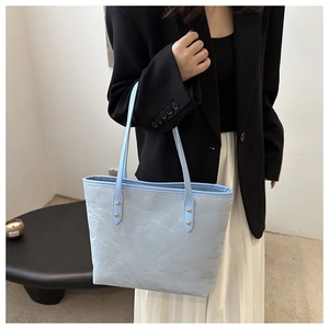 Detail of light blue pleated tote bag with gold metal rivets and soft leather texture
