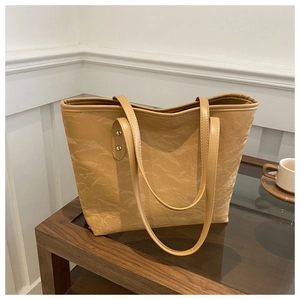 Detail view of a large camel tote bag featuring unique pleated texture and gold rivets