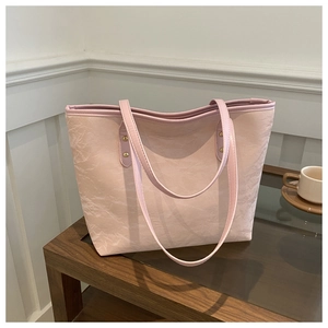 Macro shot of light pink tote bag showing wrinkled leather texture and golden metal rivets