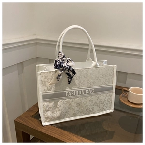 Detail of white canvas tote bag with gray floral print and silk scarf accessory