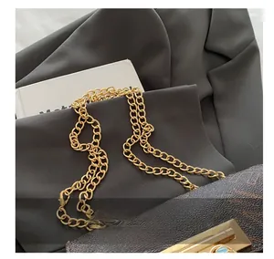 Detail view of golden metal chain strap and retro geometric patterns on the brown bag