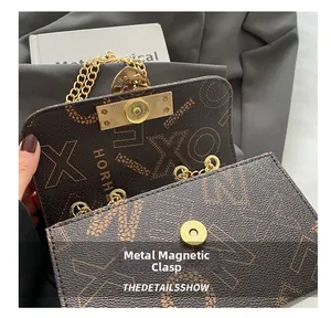 Detail of the golden metal clasp and chain on the brown letter print crossbody bag