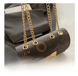 Close-up of golden chain straps and letter print detail on brown leather bucket bag