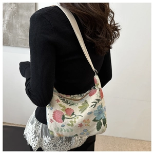 Close-up of floral jacquard crescent bag with colorful embroidery and canvas strap