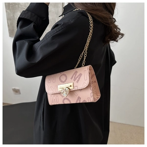 Detail of pink leather crossbody bag with gold heart-shaped diamond clasp and chain