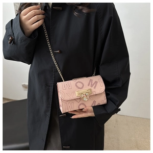 Detail of pink small crossbody bag featuring colorful gem heart lock and chain strap