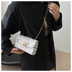 Close-up of white leather handbag featuring heart-shaped gold clasp and chain strap