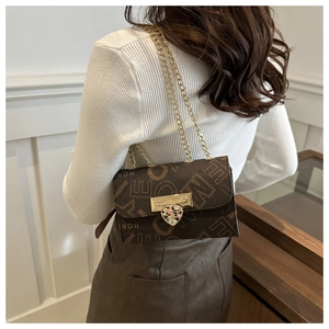 Detail of vintage brown leather bag with letter print and heart floral clasp