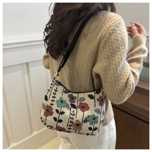 Floral jacquard crescent bag worn as a shoulder bag against a cozy knitted sweater