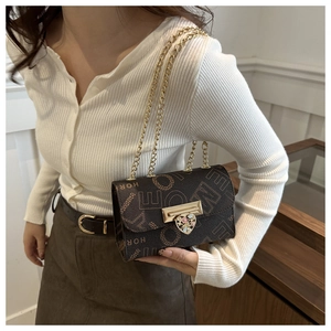 Close-up of brown leather bag with golden heart buckle and elegant chain strap details