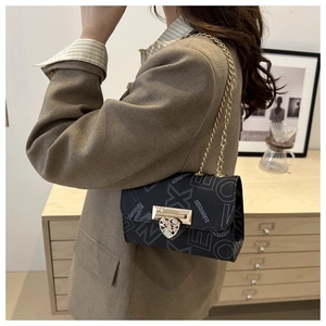 Detail of black leather crossbody bag with letter print and heart-shaped gold lock