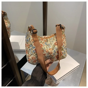 Close-up of vintage floral crescent bag featuring adjustable brown nylon strap and woven fabric