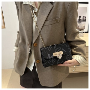 Detail of black leather square bag with white letter prints and heart-shaped metal buckle