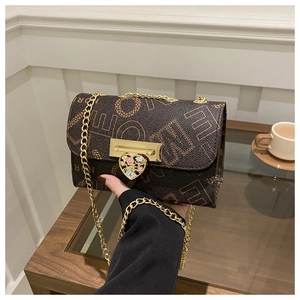 Detailed close-up of dark brown handbag with gold chain strap and heart-shaped flower lock