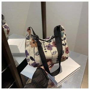 Detail of floral tapestry fabric and adjustable black strap on a crescent hobo bag