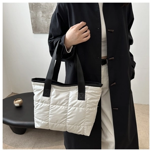 Vue latérale d'une femme portant un sac cabas matelassé blanc avec anses noires