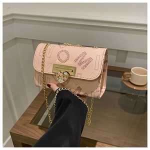 Detailed close-up of pink chain bag with heart buckle and colorful jewel embellishment