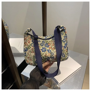 Detail of floral jacquard crescent bag featuring vintage patterns and blue canvas strap