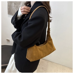 Détail du sac hobo en daim marron avec texture mate et fermeture éclair métallique chic