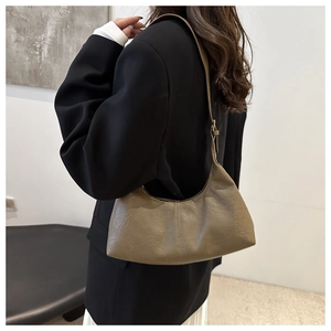 Détail du sac croissant vintage en cuir PU kaki avec texture plissée porté à l'épaule