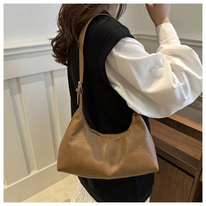 Détail macro du sac demi-lune marron camel avec texture de cuir plissé rétro