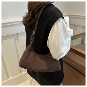 Détail du sac croissant en daim marron foncé avec boucle dorée et surpiqûres
