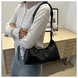 Gros plan d'un sac cabas en suédine noire porté par un mannequin en intérieur