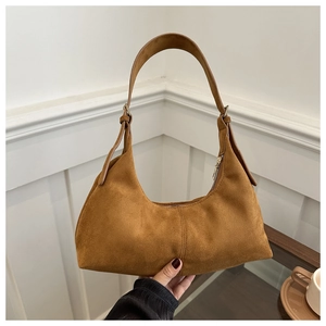 Gros plan du sac hobo en daim marron avec fermeture éclair dorée et couture fine